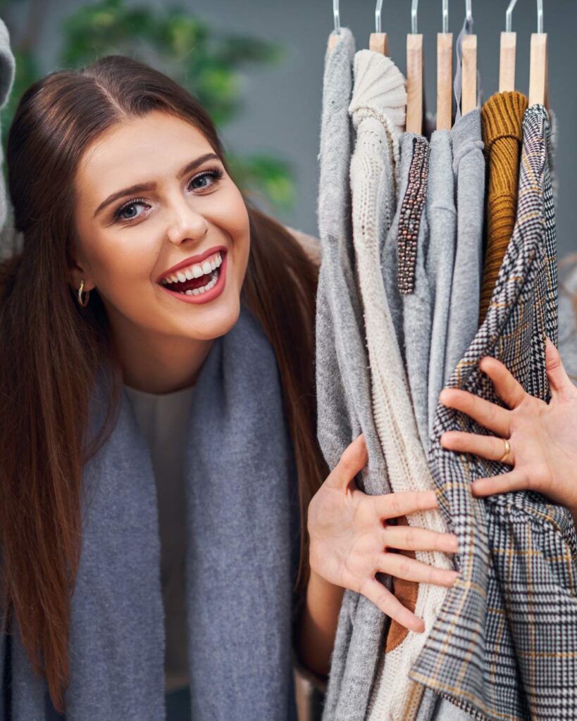frau schaut zwischen kleidung im kleiderschrank